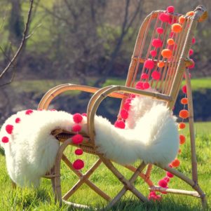 PomPom Galore Festival Orange & Pink combo neon pompoms on chair with sheepskin